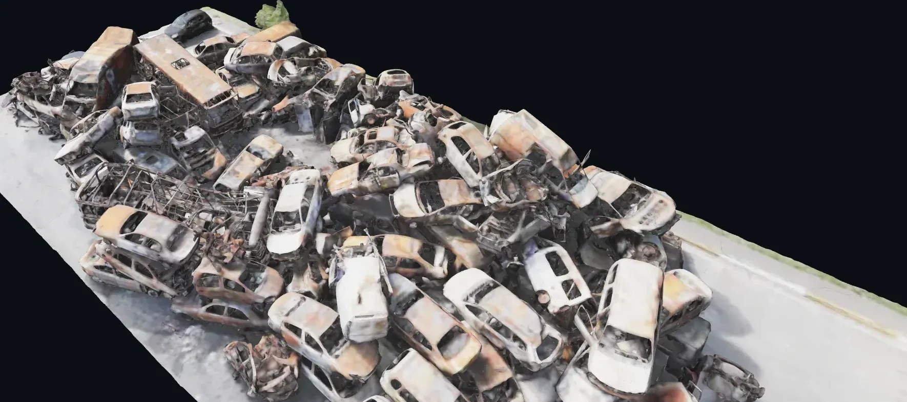 An aerial view of a scrapyard, packed with dozens of burnt-out and stripped car bodies